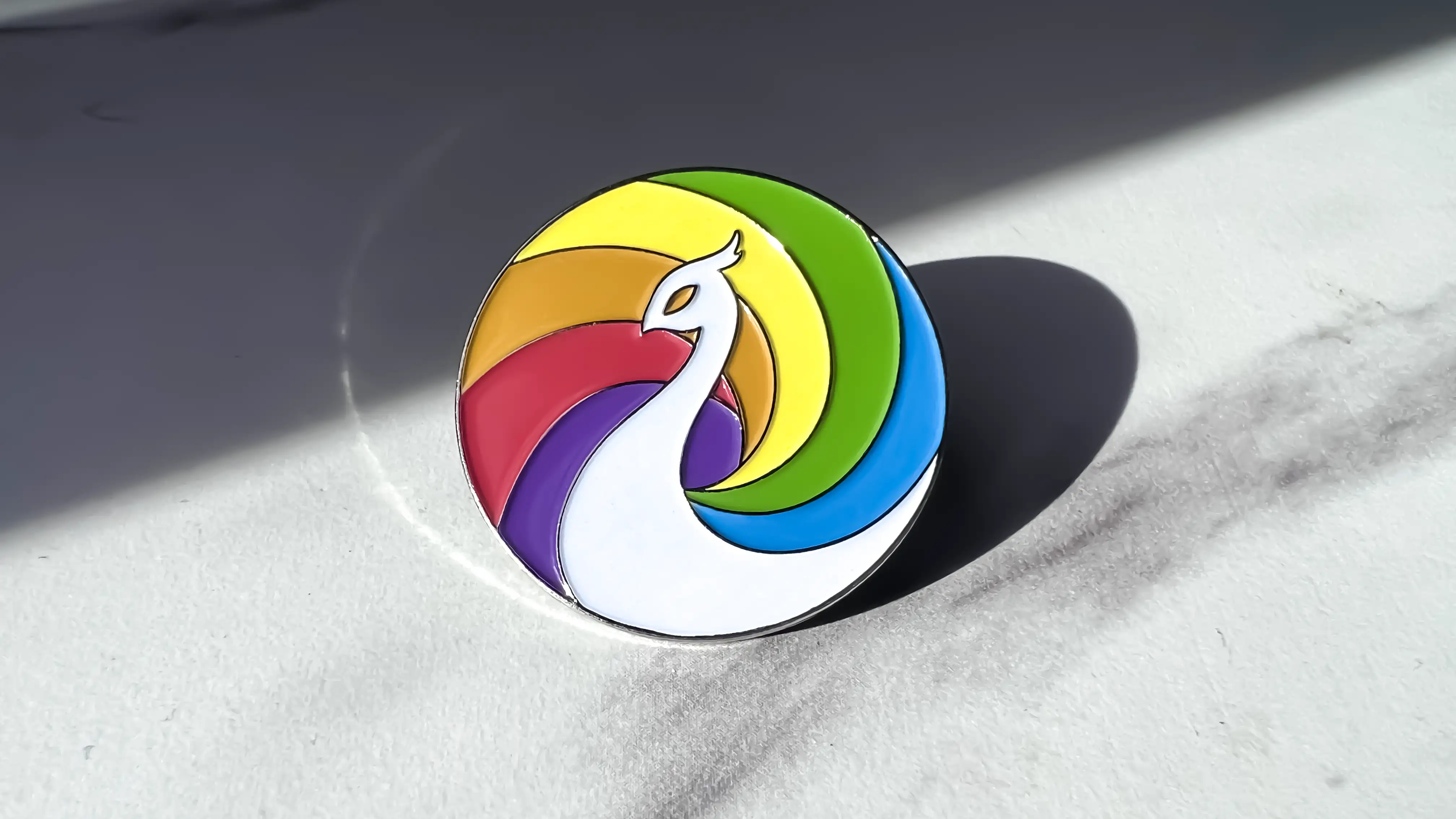 An enamel pin of the Queer Center logo by Dusty Drake