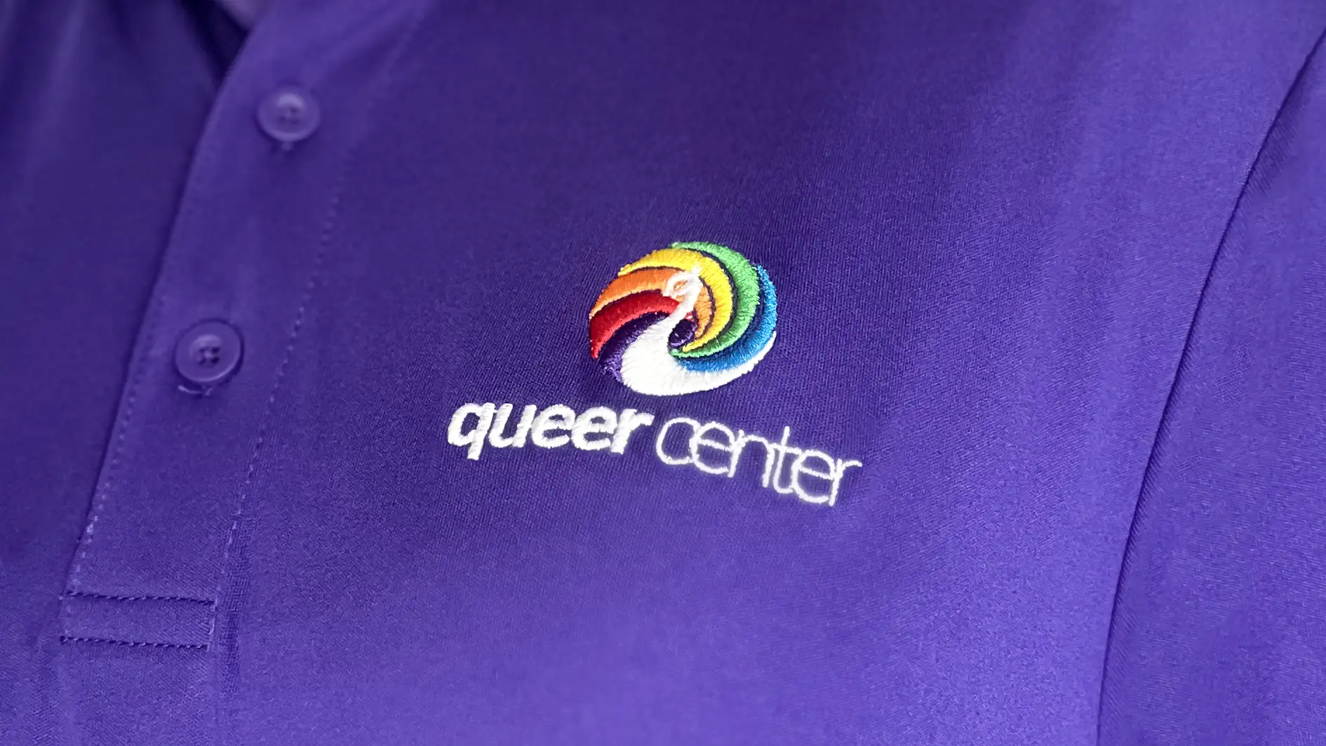 Queer Center logo by Dusty Drake embroidered on a shirt